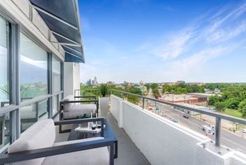 A balcony with a table and chairs overlooking a busy street.at Iris Luxury Apartments, Memphis, TN 38105  